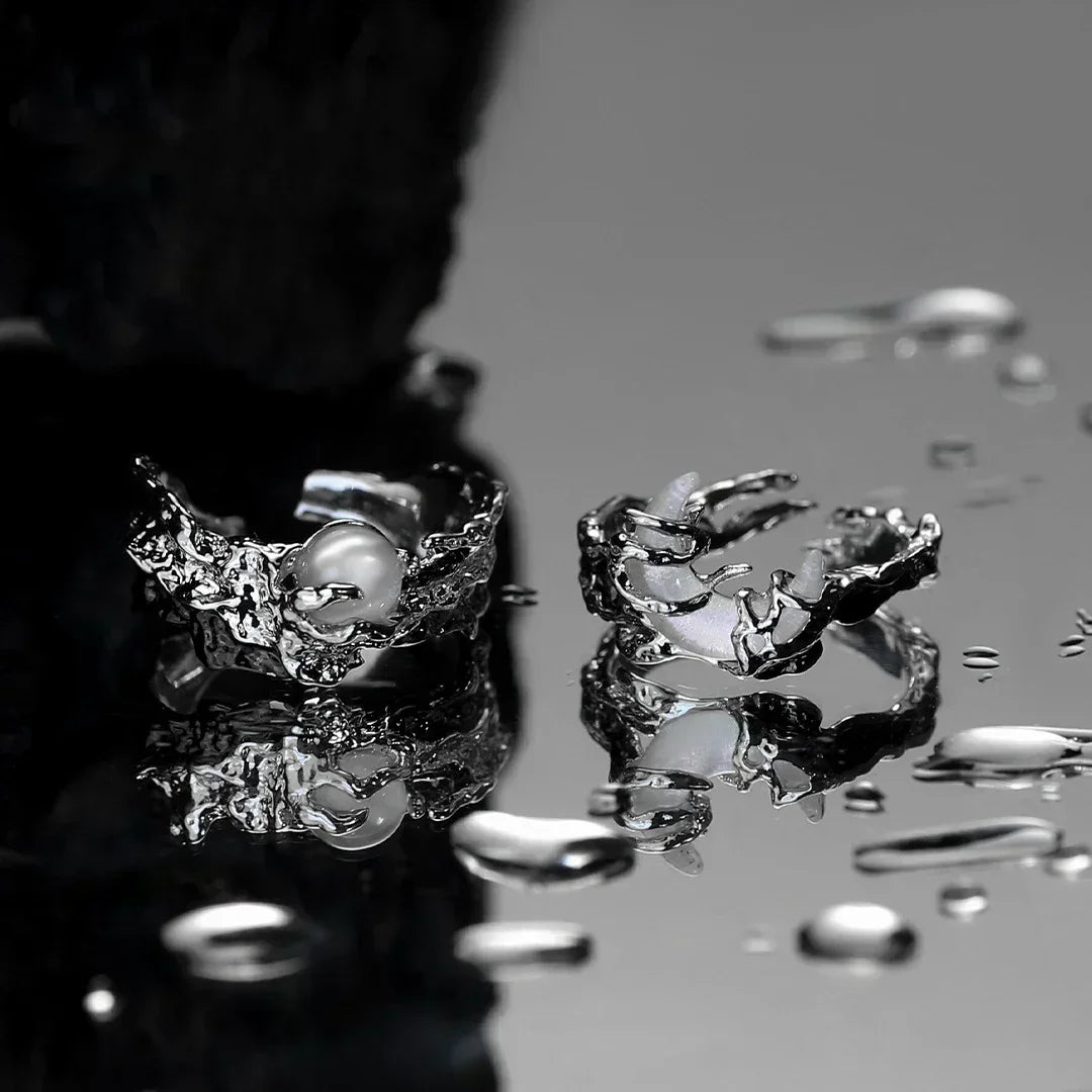 Close-up of a silver ring with a pearl on a reflective surface