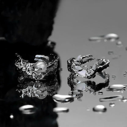 Close-up of a silver ring with a pearl on a reflective surface