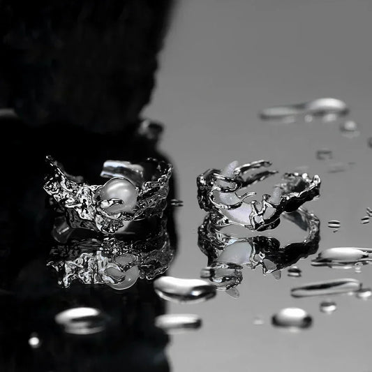 Close-up of a silver ring with a pearl on a reflective surface