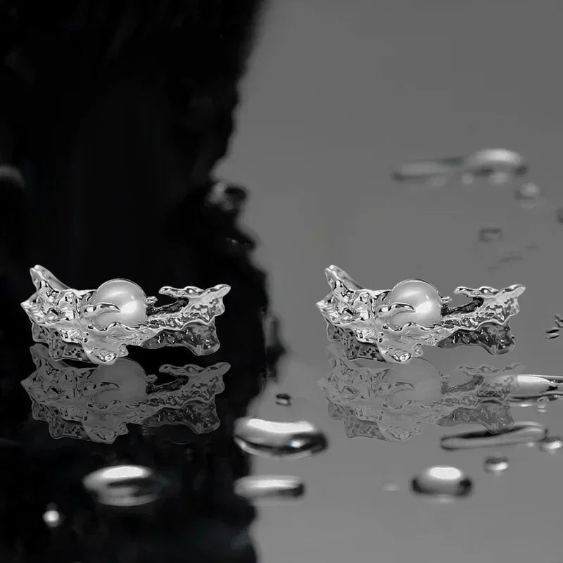 Silver rings with pearls on a reflective surface
